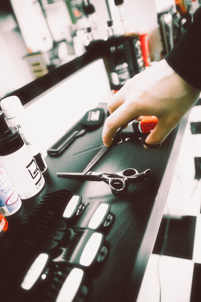 A hand reaches for scissors in a vibrant barber shop setting in Valencia, Spain.